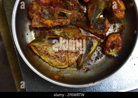 Überhängender Schuss verschiedener Fischstücke, die auf einer Pfanne mit Öl darin braten. Es wird in indischem Stil gekocht, der in Kerala und Südindien gefunden wird. Stockfoto