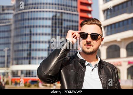 Ein attraktiver Mann mit schwarzer Lederjacke und dunkler Sonnenbrille Stockfoto