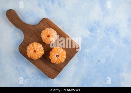 Drei frisch geschälte Mandarinen auf Holzschneidebrett Stockfoto