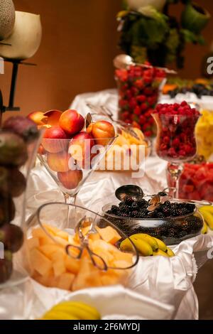 Die Hochzeitszeremonie bot einen Obsttisch mit Pfirsichen, stacheligen Birnen, Erdbeeren, Brombeeren, Melone und Bananen in Glasbehältern Stockfoto