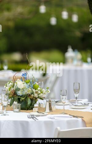 Weiße Tischdecken für einen Hochzeitsempfang im Freien mit Blaue Blumen als Dekor Stockfoto