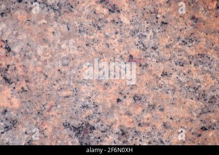 Natürlicher brauner Granit, eine flache Oberfläche aus poliertem Stein mit kleinen schwarzen Flecken. Hintergrund, Muster, Textur. Stockfoto