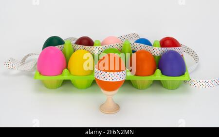 osterei auf einem Holzständer. Bunte Eier in Box. Kunststoffverpackung. Verziert mit einem festlichen Band. Stockfoto