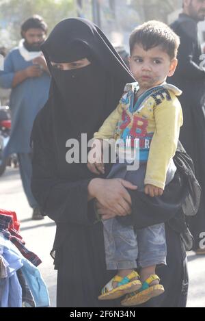 Lahore, Pakistan. April 2021. Pakistanische Familienmitglieder reisen zu Fuß, weil sie wegen der Schließung von Speedo-Bussen und der Orange Line Metro Train (OLMT) wegen neuer Beschränkungen, die die Ausbreitung des Covid-19 in der Provinzhauptstadt Lahore eindämmen, Schwierigkeiten haben. (Foto von Rana Sajid Hussain/Pacific Press) Quelle: Pacific Press Media Production Corp./Alamy Live News Stockfoto