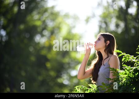 Gesunde Frau Trinkwasser aus der Flasche. Bleib Hydratation Konzept. Nicht Verhidrated. Einheit mit der Natur, im Freien. Stockfoto