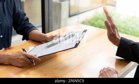 Selbstbewusster Manager eines Geschäftsmannes, der ein Angebot von Geld zur Vereinbarung eines Vertrags vom Partner ablehnt oder das Konzept von Bestechung, Bestechung und Korruption ablehnt Stockfoto