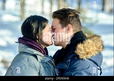 Junges Paar küsst sich im Freien in einem Winterpark aus nächster Nähe Stockfoto