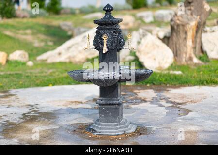 Schöner schwarzer Trinksäulenbrunnen mit Wasserhähnen auf der Straße in der antiken Touristenstadt Hierapolis, Pamukkale, Türkei. Stockfoto