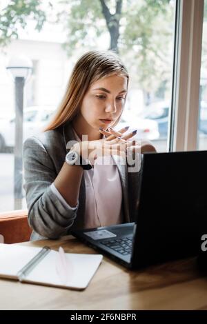 Texter, Inhaltsersteller, Remote Copywriting. Junge freiberufliche Mitarbeiterin, die mit einem Laptop im Café oder Büro auf der Tastatur tippt. Texter arbeitet Stockfoto