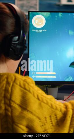 Pro Gamer spielt im Weltraum-Shooter auf dem PC. Frauen spielen mit Teamkollegen über Kopfhörer während Online-eSport-Turnier in Aktion mit Technologie Netzwerk drahtlos aufgenommen Stockfoto
