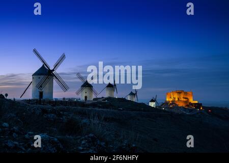 Ein Blick auf die Windmühlen und das Schloss von Consuegra in La Mancha in Zentralspanien bei Einbruch der Dunkelheit Stockfoto