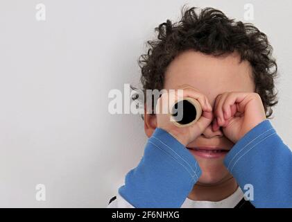 Junge Blick durch Fernglas Papierrolle auf weißem Hintergrund Stock Foto Stockfoto