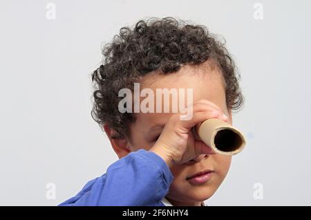 Junge Blick durch Fernglas Papierrolle auf weißem Hintergrund Stock Foto Stockfoto