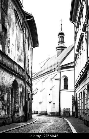 Eine gepflasterte Straße und eine Kirche in der Altstadt von Krakau in Polen. Stockfoto