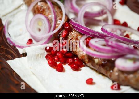 Ein Gericht, das auf dem Dönergrill gekocht wird. Georgische Gerichte. Garniert mit Zwiebeln und Granatapfelkernen Stockfoto