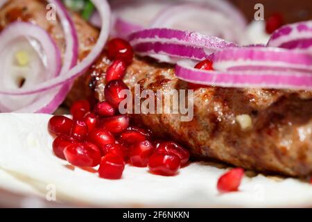 Ein Gericht, das auf dem Dönergrill gekocht wird. Georgische Gerichte. Garniert mit Zwiebeln und Granatapfelkernen Stockfoto