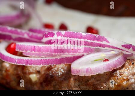 Ein Gericht, das auf dem Dönergrill gekocht wird. Georgische Gerichte. Garniert mit Zwiebeln und Granatapfelkernen Stockfoto