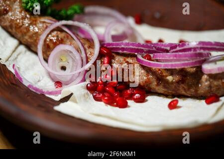 Ein Gericht, das auf dem Dönergrill gekocht wird. Georgische Gerichte. Garniert mit Zwiebeln und Granatapfelkernen Stockfoto
