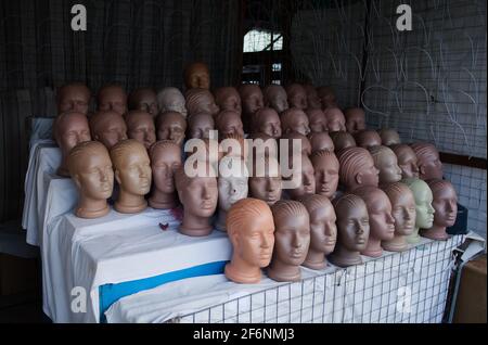 Reihen weiblicher Kopfpuppen auf dem Straßenmarkt Verkäufer. Kunststoffdummy-Köpfe in einer Reihe im leeren Straßenladen. Ukraine. Stockfoto