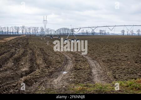 Mobiles Bewässerungssystem für Ackerland. Das Foto wurde an einem bewölkten Tag aufgenommen. Weiches Licht. Stockfoto