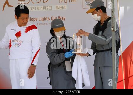 Iida, Japan, 02/04/2021, olympische Fackelveranstaltung in iida. Menschen auf der Bühne, die das Feuer für die Fackel vorbereiten und anzünden. Stockfoto