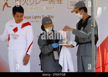 Iida, Japan, 02/04/2021, olympische Fackelveranstaltung in iida. Menschen auf der Bühne, die das Feuer für die Fackel vorbereiten und anzünden. Stockfoto