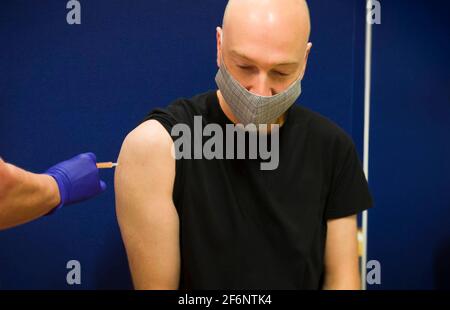 Weißer Mann mittleren Alters, kaukasischer Mann mit Gesichtsmaske, erhält eine Covid 19-Impfstoffinjektion, England, Großbritannien Stockfoto