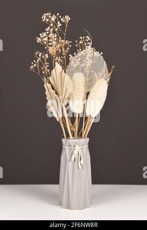 Getrocknete natürliche Blumen Bouquet in grauer Vase mit Blumen und Blättern wie Palmblatt, Skelett Blatt, Luffa und gemeinsame Gypsophila Blumen Stockfoto