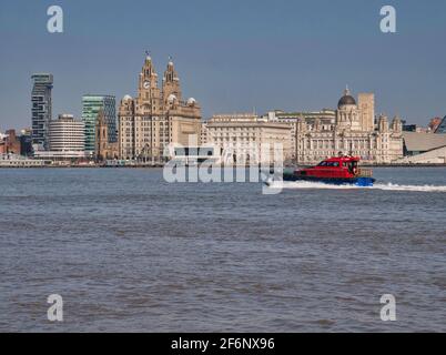 Ein Pilotboot fährt an den historischen Three Graces Buildings an der zum UNESCO-Weltkulturerbe gehörenden Hafenpromenade von Liverpool am Fluss Mersey, Großbritannien, vorbei Stockfoto