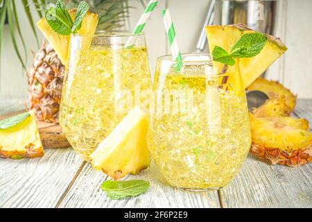 Ananas- und Limettengetränk, Limonadencocktail mit geschnittenen Ananas und Scheiben, auf weißem Holzhintergrund mit tropischen Blättern und Barschablonen Kopie sp Stockfoto