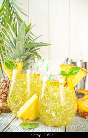 Ananas- und Limettengetränk, Limonadencocktail mit geschnittenen Ananas und Scheiben, auf weißem Holzhintergrund mit tropischen Blättern und Barschablonen Kopie sp Stockfoto
