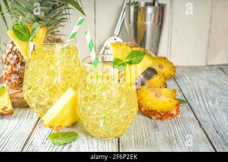 Ananas- und Limettengetränk, Limonadencocktail mit geschnittenen Ananas und Scheiben, auf weißem Holzhintergrund mit tropischen Blättern und Barschablonen Kopie sp Stockfoto