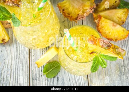 Ananas- und Limettengetränk, Limonadencocktail mit geschnittenen Ananas und Scheiben, auf weißem Holzhintergrund mit tropischen Blättern und Barschablonen Kopie sp Stockfoto