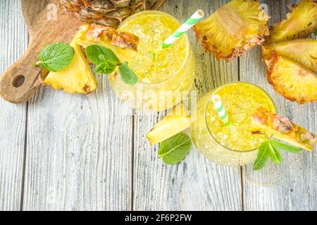 Ananas- und Limettengetränk, Limonadencocktail mit geschnittenen Ananas und Scheiben, auf weißem Holzhintergrund mit tropischen Blättern und Barschablonen Kopie sp Stockfoto