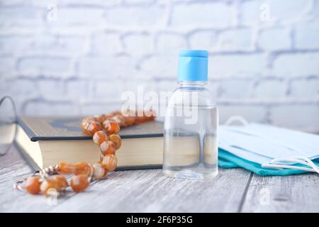 Chirurgische Masken, Händedesinfektionsmittel, Stechbuch des quran auf hölzernen Hintergrund Stockfoto