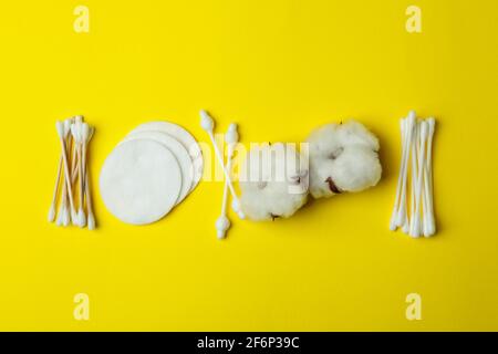 Wattestäbchen, Pads und Blumen auf gelbem Hintergrund Stockfoto