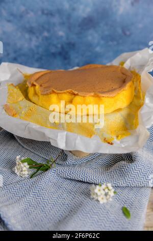 Portugiesischer Biskuitkuchen, eingewickelt in das typische Backpapier, auf Holzhintergrund mit bemaltem ostereier-Dekor. Stockfoto