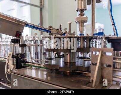 Der Prozess des Verdrehens der Deckel auf Plastikflaschen. Wasserproduktion. Stockfoto