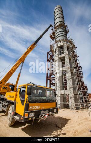 Aktau, Kasachstan - 19. Mai 2012: Bau einer asphaltischen Bitumenfabrik Raffineriesäule. Metalldestillationsturm und hydraulischer Hebezeug. Stockfoto