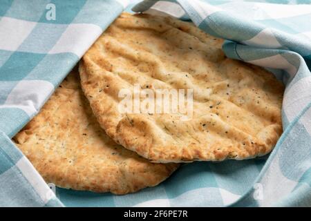 Frisch gebackenes Naan mit Knoblauch und Koriander in einem Tuch, um frisch aus der Nähe zu bleiben, Stockfoto