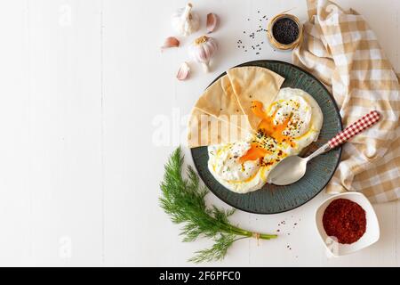 Schale mit Türkischen Cilbir Eier, Joghurt, pochierte Eier, Knoblauch, Chili, frischer Dill und zerlassener Butter. Verziert mit wenigen Stücke von lavash Brot ein Stockfoto