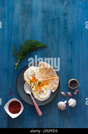 Schale mit Türkischen Cilbir Eier, Joghurt, pochierte Eier, Knoblauch, Chili, frischer Dill und zerlassener Butter. Verziert mit wenigen Stücke von lavash Brot ein Stockfoto