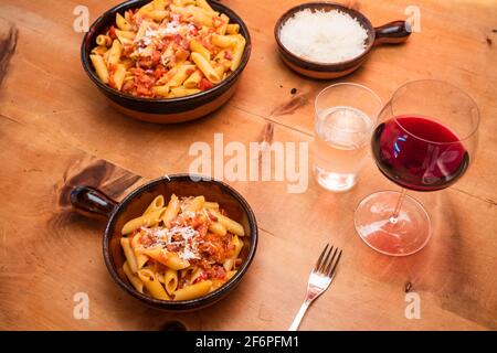 Alle Arrabiata Pasta oder Nudelgericht mit Rotwein, Parmesan auf einem rustikalen Tisch penne Stockfoto