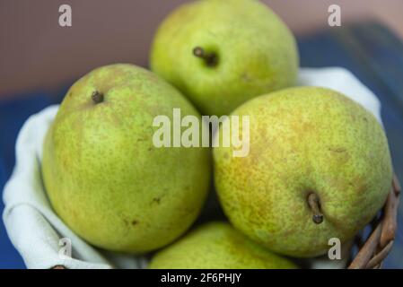 Grüne Birnenfrüchte im Holzkorb auf neutralem Hintergrund. Früchte reich an Vitamin A, Kalzium und Vitamin C. kalorienarme Lebensmittel. Infredient für Säfte und Stockfoto