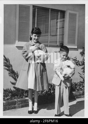 Bruder und Schwester der 1950er Jahre posieren mit Live Pet Bunnies am Ostersonntag, USA Stockfoto