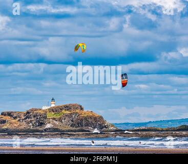 Bunte Drachen von Kitesurfern von Boardern mit Blick auf Fidra Island und Leuchtturm an einem sonnigen, windigen Tag, Firth of Forth, East Lothian, Schottland, Großbritannien Stockfoto