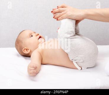 Physiotherapeutin, die Entwicklungsübung mit einem sechsmonatigen Mädchen in der Kinderklinik durchführt. Der Arzt manipuliert die Beine des Kindes, um die Flexibilität zu erhöhen Stockfoto