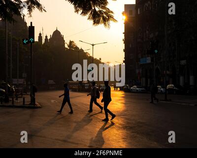 Mumbai, Indien - 7. Januar 2021: Silhouette von Menschen, die Straßen mit der Sonne im Hintergrund aufgehen und Verkehrssignal in grün auf den Straßen von Stockfoto