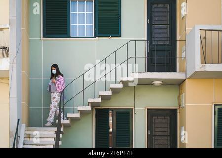 10. März 2021 - Faro, Portugal: Junge Frau verlässt ihr Haus mit Pyjama und Maske während der Sperrung aufgrund der Covid 19 Pandemie Stockfoto