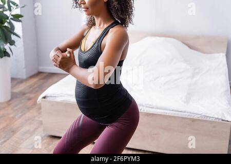 Verkürzte Ansicht einer Schwangeren afroamerikanerin im Sportswear-Training Im Schlafzimmer Stockfoto